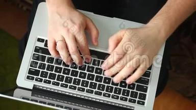 一个男人正在用笔记本电脑工作。 在键盘上键入文本。 笔记本电脑在我腿上。 从上面看。